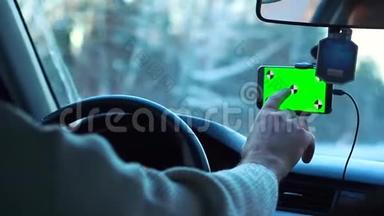 冬天开车的人。 智能手机有一个绿色的屏幕贴在<strong>挡风玻璃</strong>上，它把手指按在<strong>挡风玻璃</strong>上